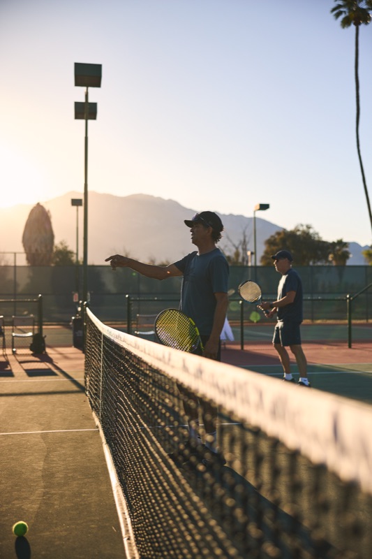 A coach directing a clinic at CC Tennis Club at golden hour, mountains behind